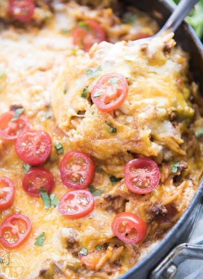 A spoonful of taco pasta topped with cheese in a pan.