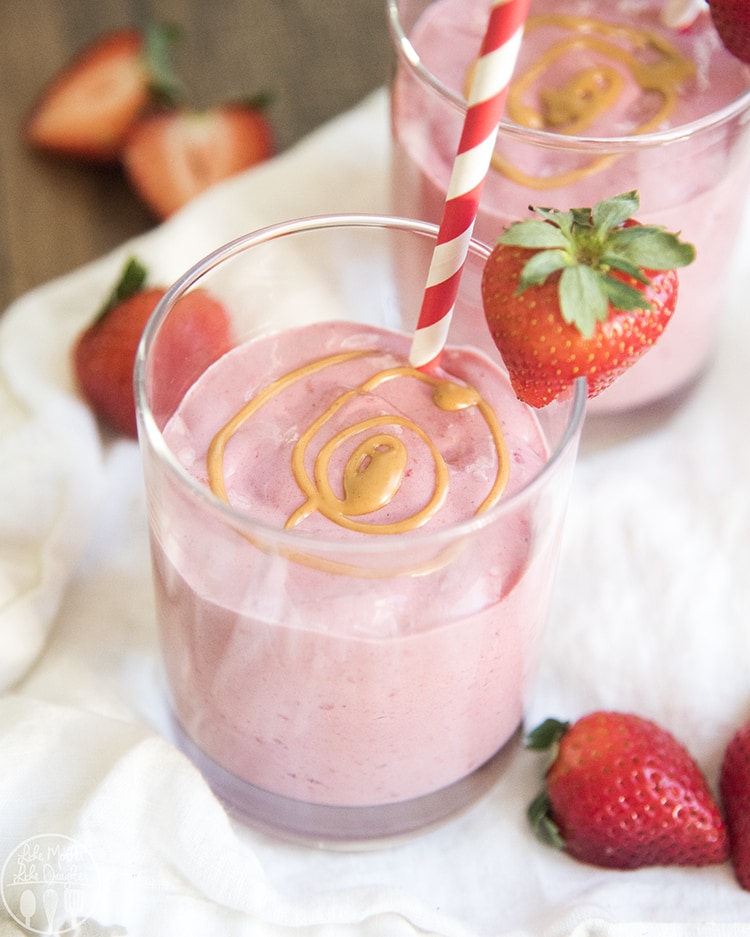 A glass of a pink smoothie with a peanut butter swirl on top. 