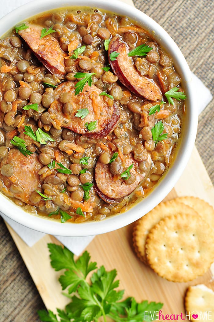 A bowl of lentils and sausage topped with parsley. 