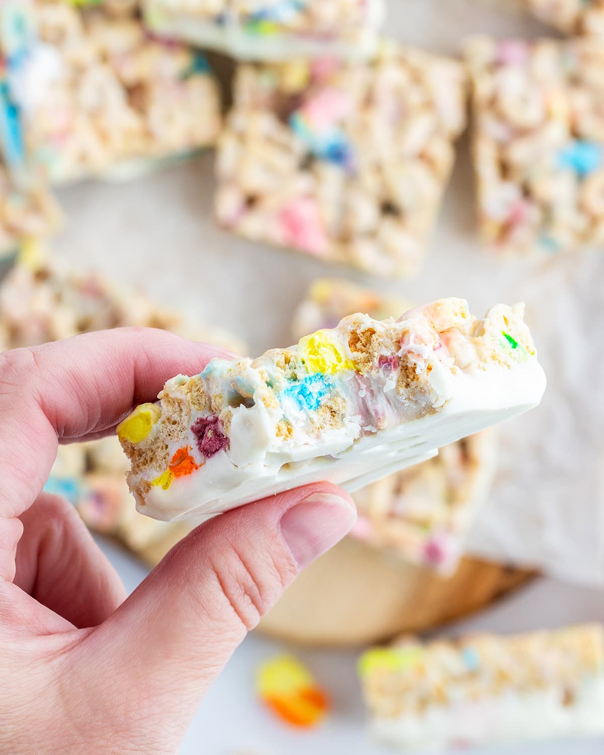 A hand holding a lucky charm rice krispie treat with a bite out of it.