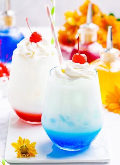 A blue colored Italian cream soda with one using a red syrup in the back.