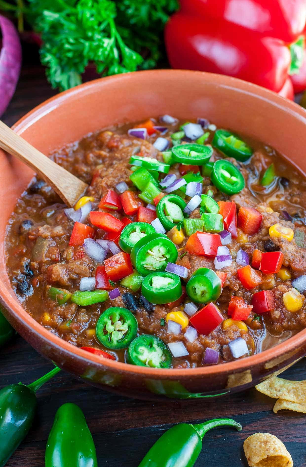 A bowl of lentil chili topped with jalapenos and red peppers. 