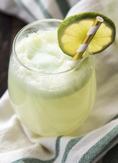 A glass of lime sherbet punch topped with a lime slice.