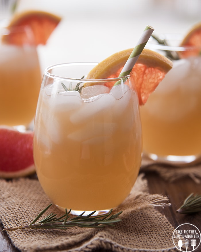 A glass of a rosemary grapefruit mocktail topped with ice. 