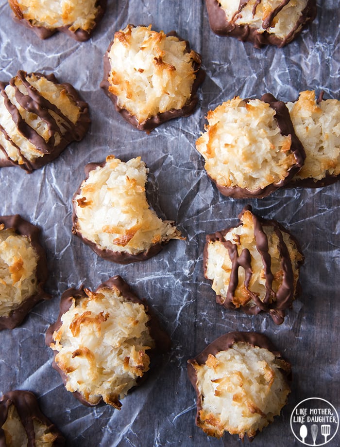 Coconut macaroons on a piece of waxed paper. Some are drizzled with chocolate. 