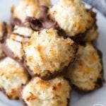 A plate of coconut macaroons, with their bottoms dipped in chocolate. They are lightly golden brown little mounds of coconut.