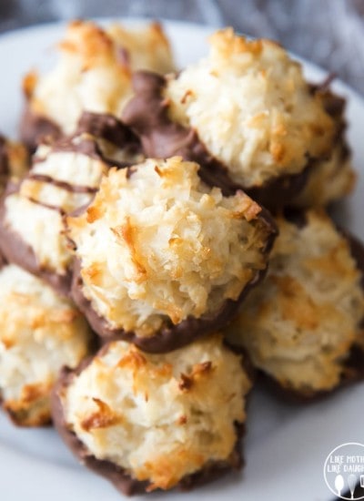 A plate of coconut macaroons, with their bottoms dipped in chocolate. They are lightly golden brown little mounds of coconut.