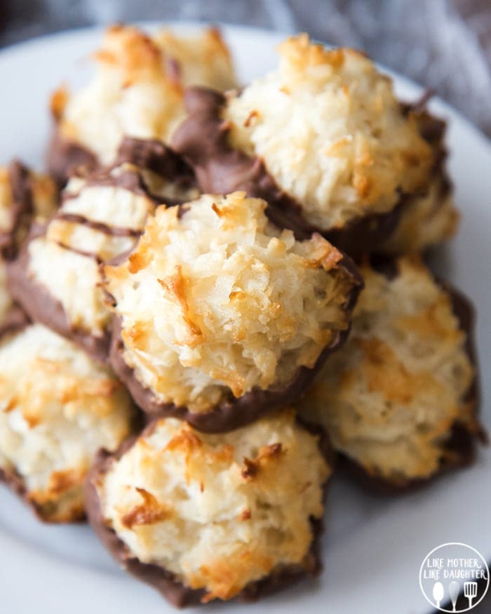 A plate of coconut macaroons, with their bottoms dipped in chocolate. They are lightly golden brown little mounds of coconut.