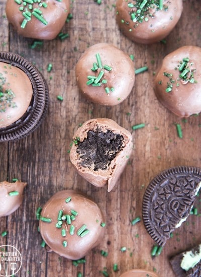 Mint Oreo truffles arranged randomly on a wooden board, with green sprinkles  and oreos.