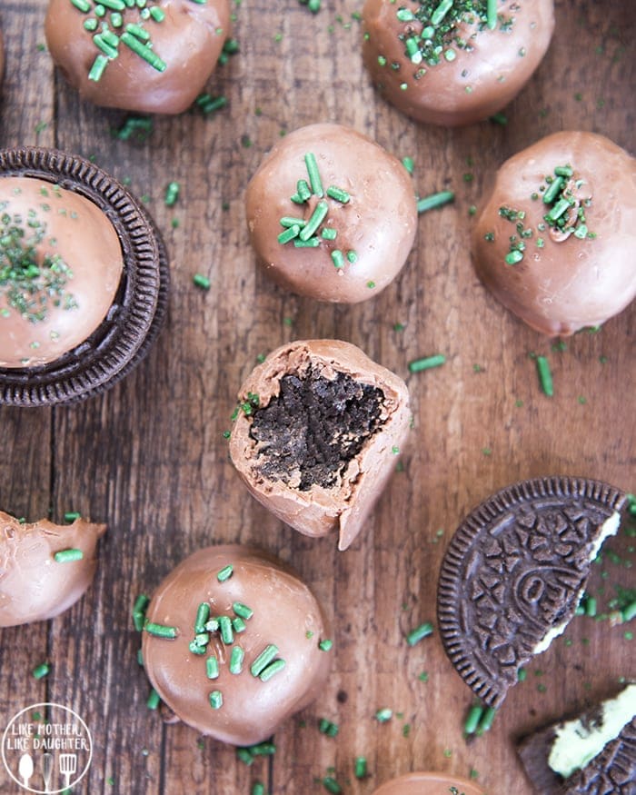 Mint Oreo truffles arranged randomly on a wooden board, with green sprinkles  and oreos.