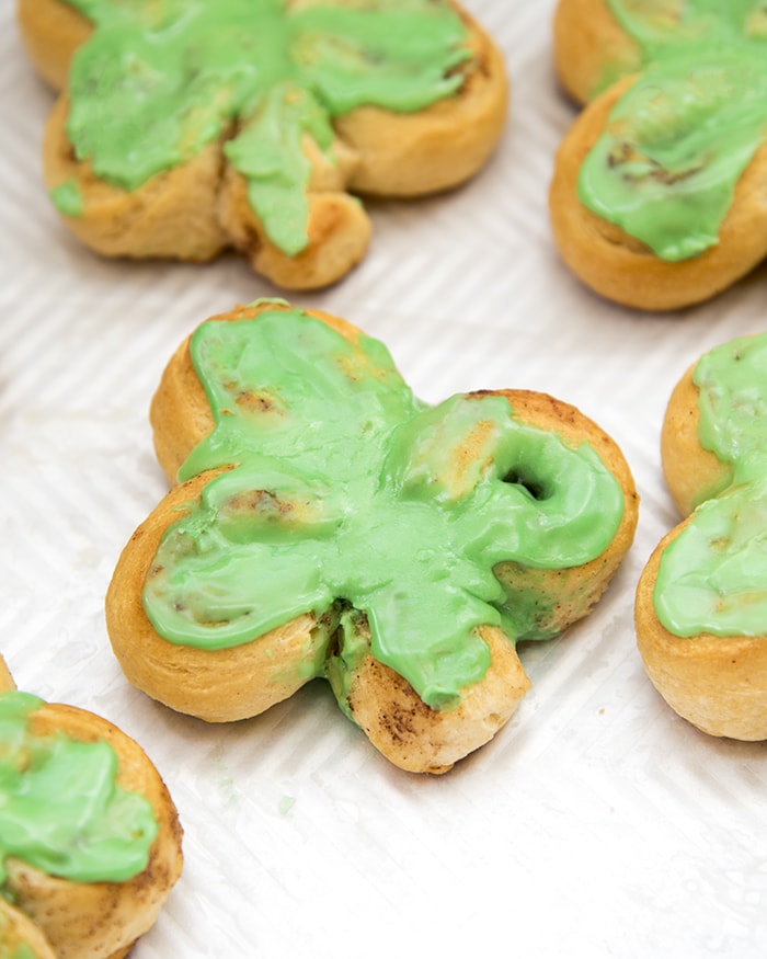 A cinnamon roll shaped like a three leaf clover topped with green icing.