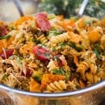 A close up of a bowl of taco pasta salad with rotini pasta, doritos, tomatoes, ground beef, and topped with cilantro.