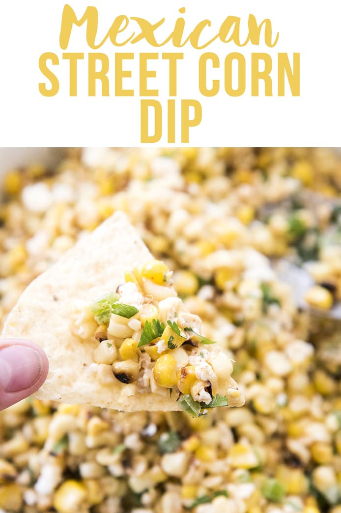 A hand holding a chip dipped into street corn dip.