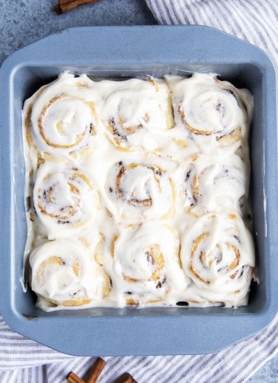 An overhead photo of 9 no yeast cinnamon rolls in a square baking pan, all topped with cream cheese frosting.