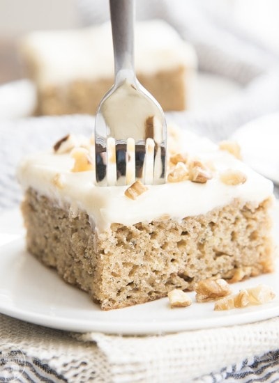 A piece of banana cake with cream cheese frosting on a plate.