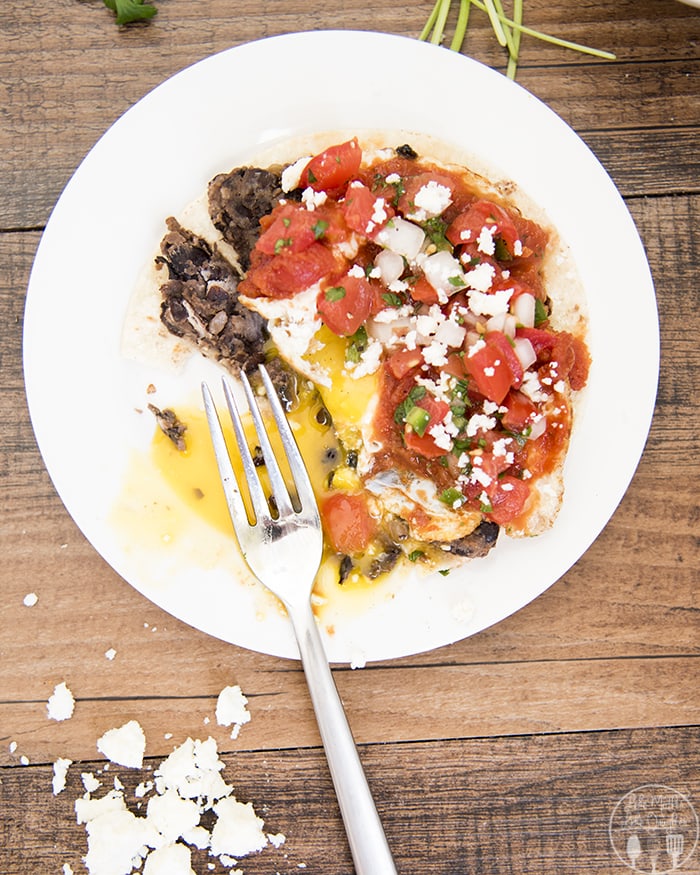 A fork cutting into huevos rancheros on a plate. 