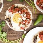 An overhead photo of huevos rancheros with salsa and cotija cheese.