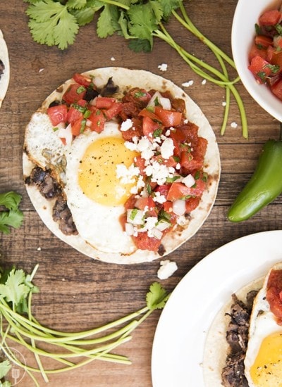 An overhead photo of huevos rancheros with salsa and cotija cheese.