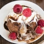 A chocolate molten laval cake topped with ice cream and fresh raspberries.