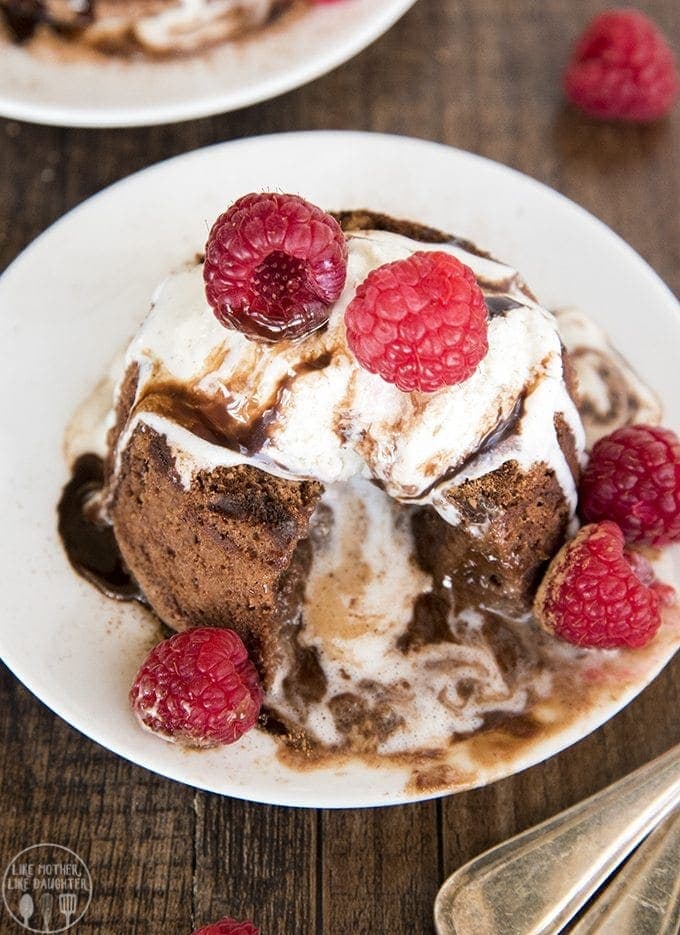 A chocolate molten laval cake topped with ice cream and fresh raspberries.