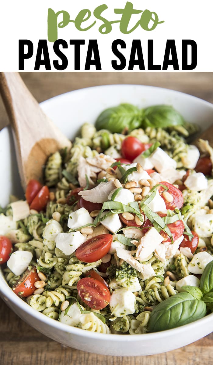 A bowl of pesto pasta salad with chicken, tomatoes, and fresh mozzarella. 
