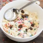 A bowl of sugar cookie dough with sprinkles, chocolate chips, and white chocolate chips.