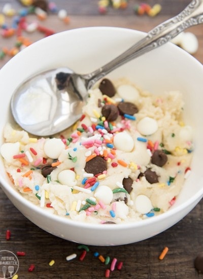 A bowl of sugar cookie dough with sprinkles, chocolate chips, and white chocolate chips.