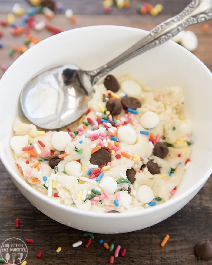 A bowl of sugar cookie dough with sprinkles, chocolate chips, and white chocolate chips.