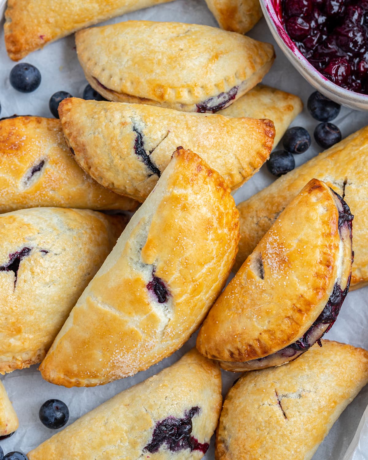 A pile of golden brown hand held blueberry pies.