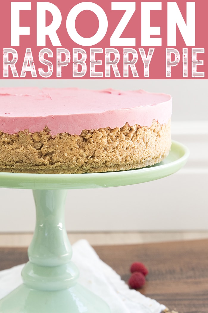 A frozen raspberry pie with a graham cracker crust on a green cake stand. 