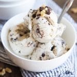 A bowl of banana ice cream topped with chocolate chunks and walnuts.