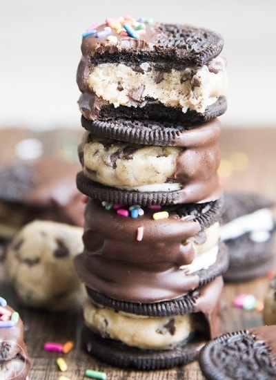 A stack of Oreos stuffed with cookie dough and dipped in melted chocolate.