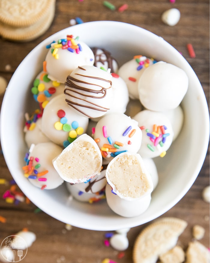A bowl of golden oreo truffles topped with white chocolate and sprinkles.