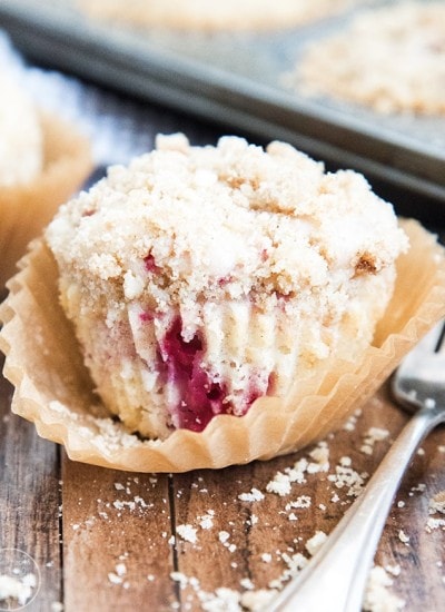 A raspberry muffin with a streusel topping in a muffin liner.