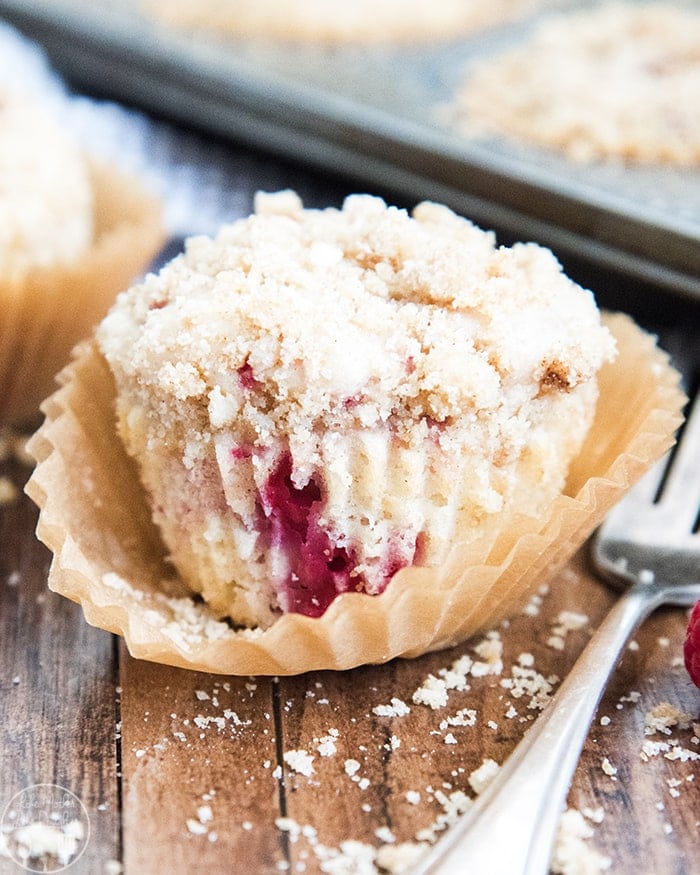 A raspberry muffin with a streusel topping in a muffin liner.