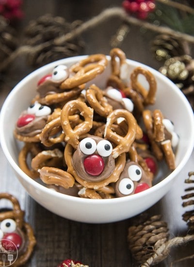 A bowl of rolo pretzel reindeer treats decorated with candy eyes to look like reindeer.