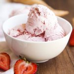 A white bowl full of scoops of homemade strawberry ice cream.