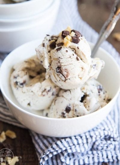 A bowl of banana ice cream topped with chocolate chunks and walnuts.