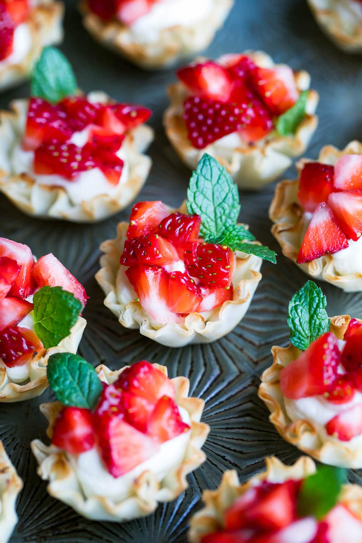 Phyllo cups filled with feta and diced strawberries with fresh mint leaves on them. 