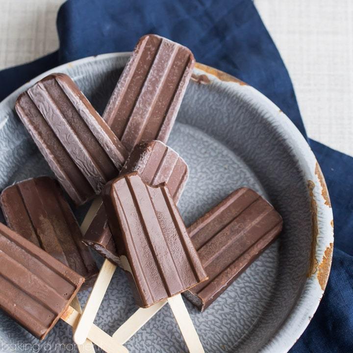 Chocolate popsicles arranged randomly on a round baking tray.
