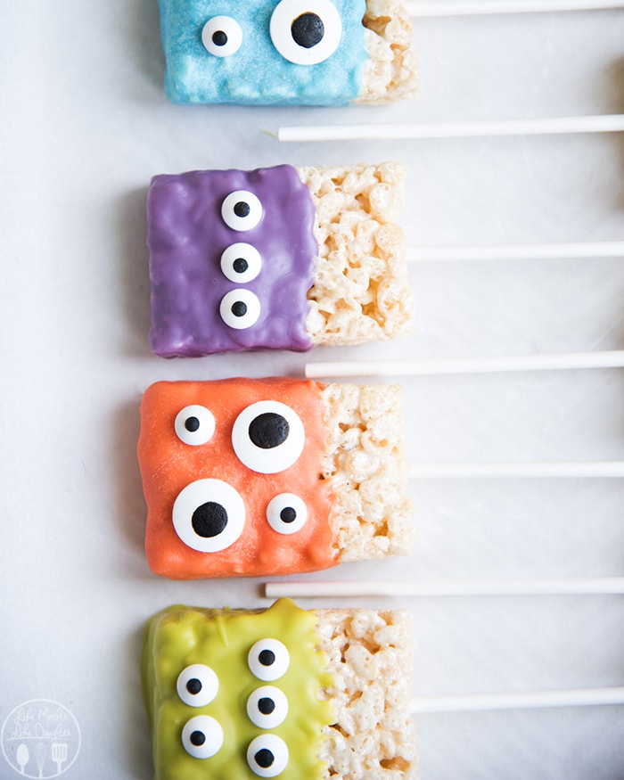 A row of Halloween rice krispie treats on a stick decorated to look like cute monsters. 