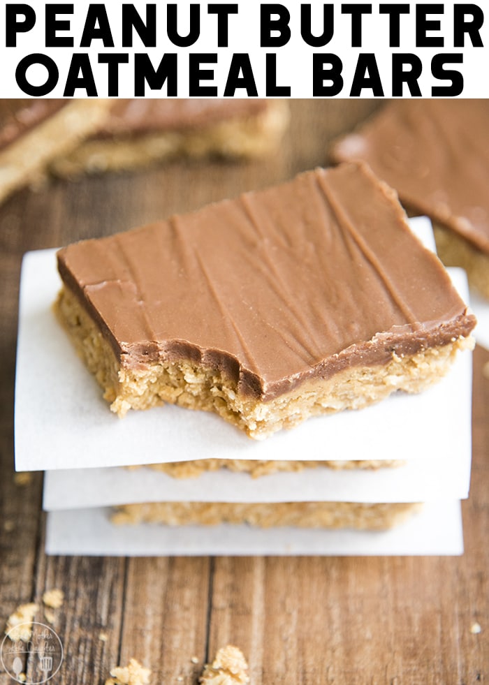 A stack of peanut butter bars with chocolate topping and a bite taken out of the top one.