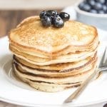 A stack of ricotta pancakes topped with fresh blueberries.