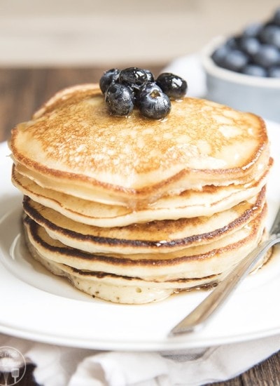 A stack of ricotta pancakes topped with fresh blueberries.