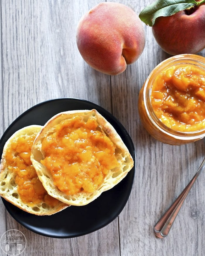 Peach jam spread on two halves of an English muffin.