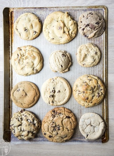 A bunch of different chocolate chip cookies on a cookie sheet.