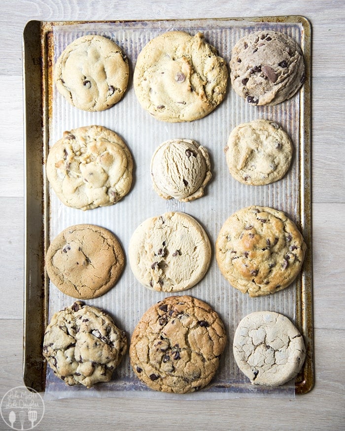 A bunch of different chocolate chip cookies on a cookie sheet.