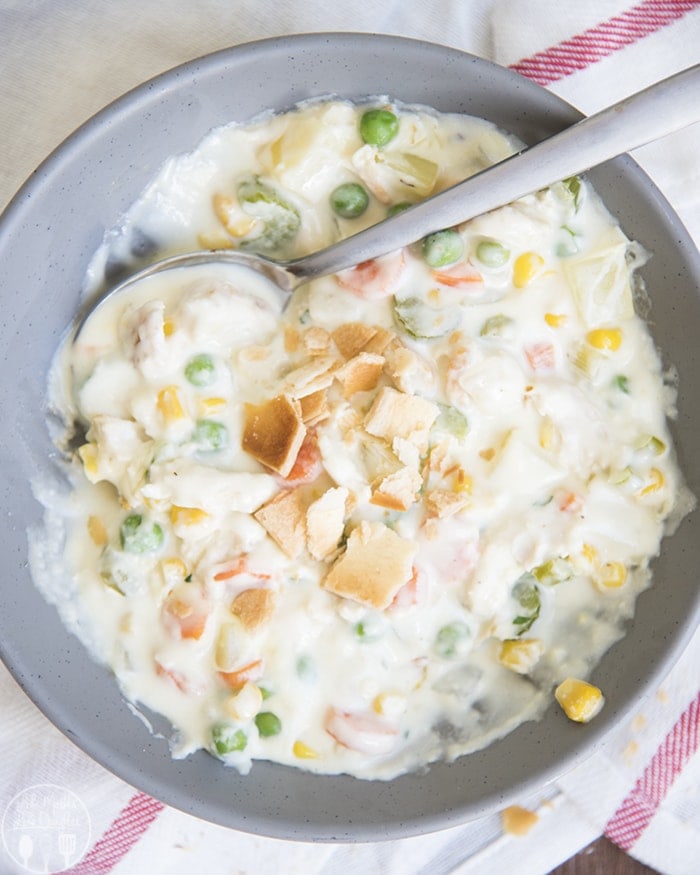 A gray bowl full of chicken pot pie soup with pie crust pieces in the middle.