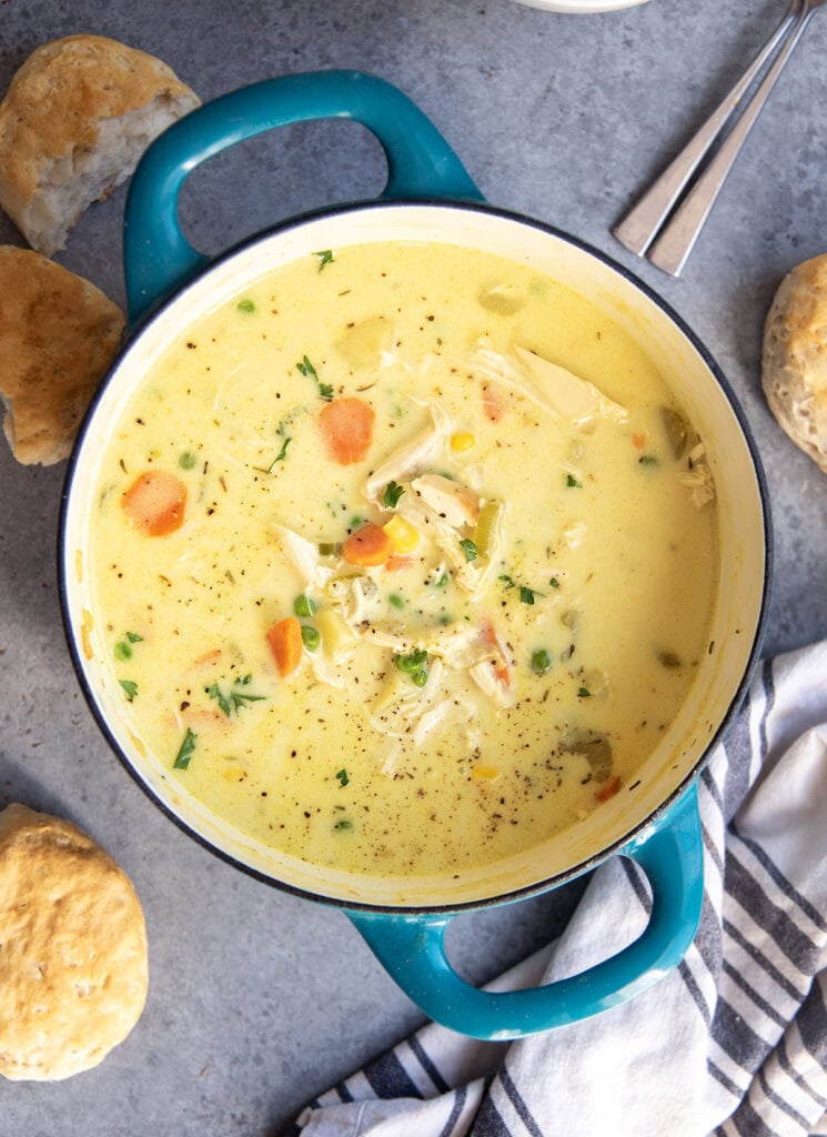 A pot of chicken pot pie soup with shredded chicken, carrots, celery, corn, and potatoes.