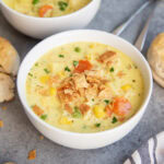 A bowl of chicken pot pie soup with carrots, chicken, corn, and topped with pie crust pieces.